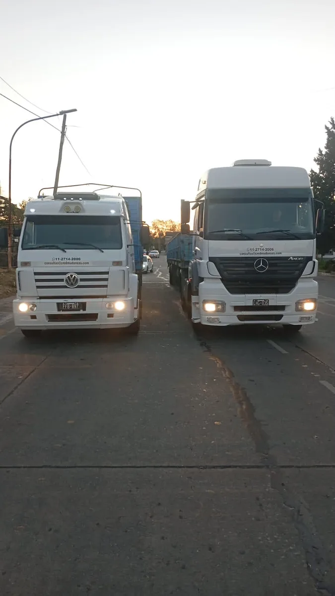 Dos camiones de la flota de Mudandome de frente al atardecer en la ruta