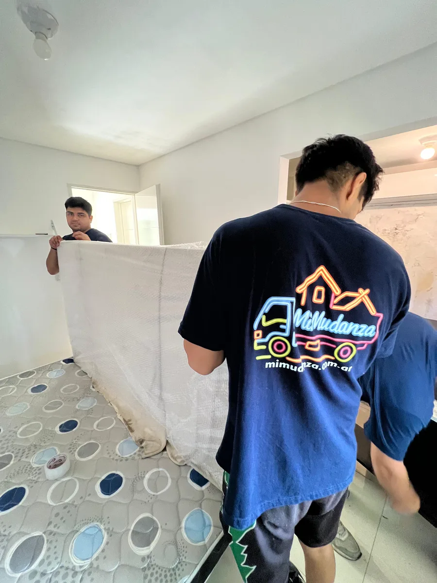 Equipo de Mudandome embalando un colchón con film protector dentro de una vivienda